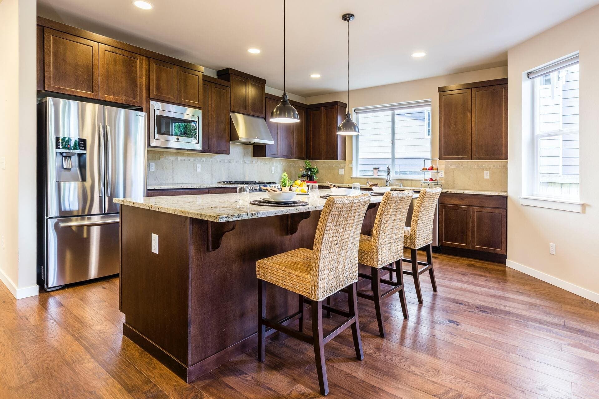 Kitchen with dark wood cabinets, a granite-topped island and woven bar stools