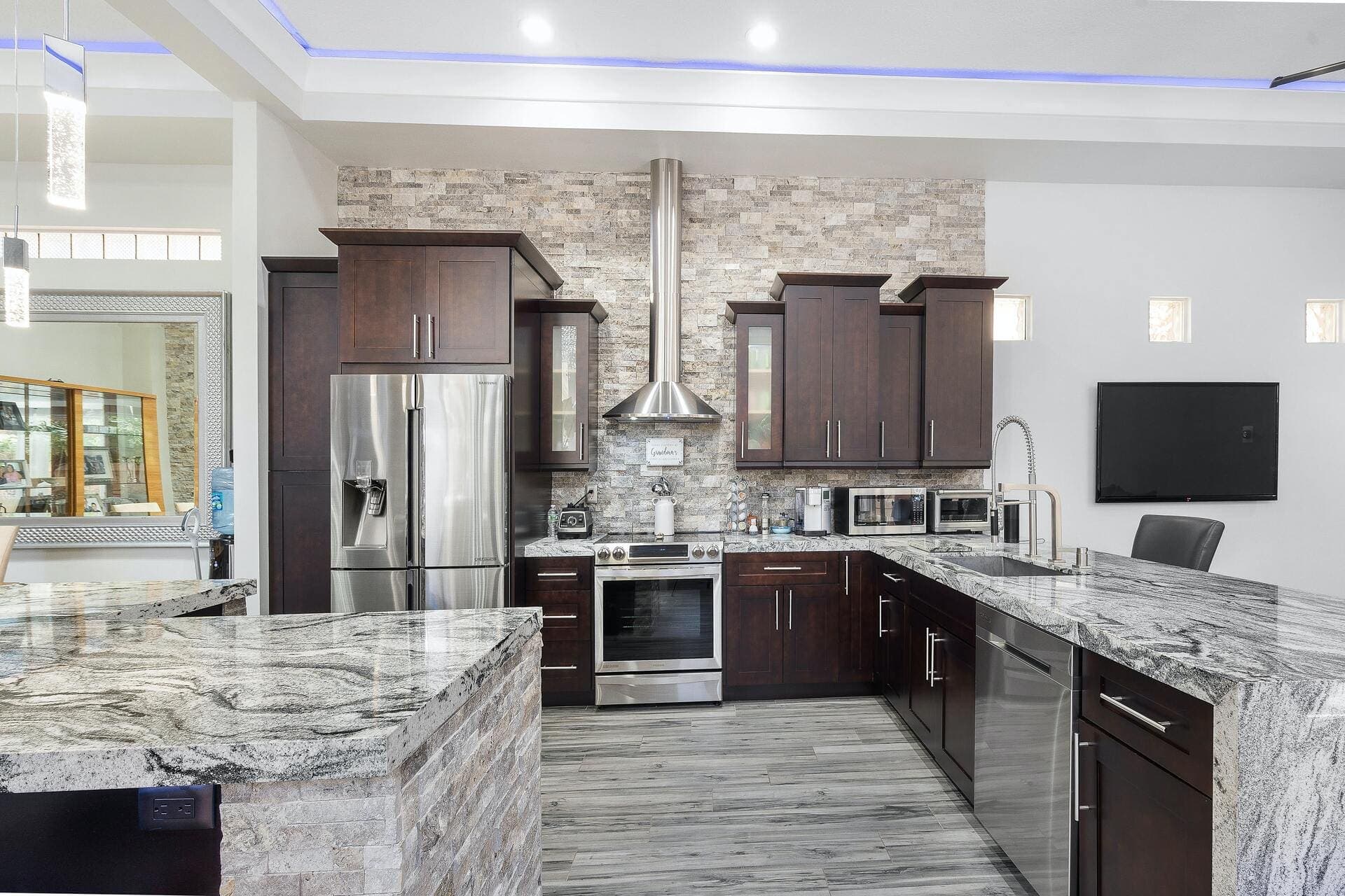 Kitchen with waterfall-edge granite counters and a stacked-stone feature wall